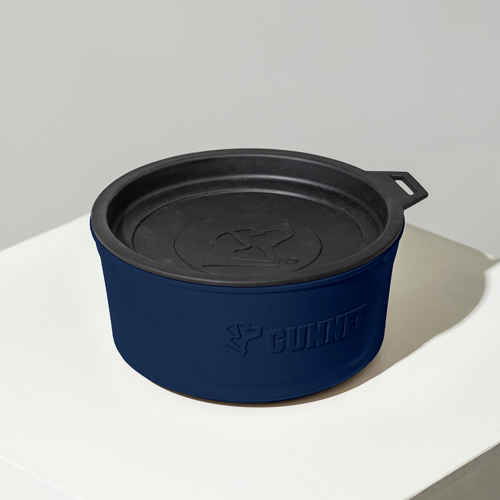 The GUNNER DOG BOWL - NAVY is a limited-edition round pet bowl in navy and black, with a lid and embossed GUNNER logo, displayed on a white surface as part of the exclusive Color Fetch collection.