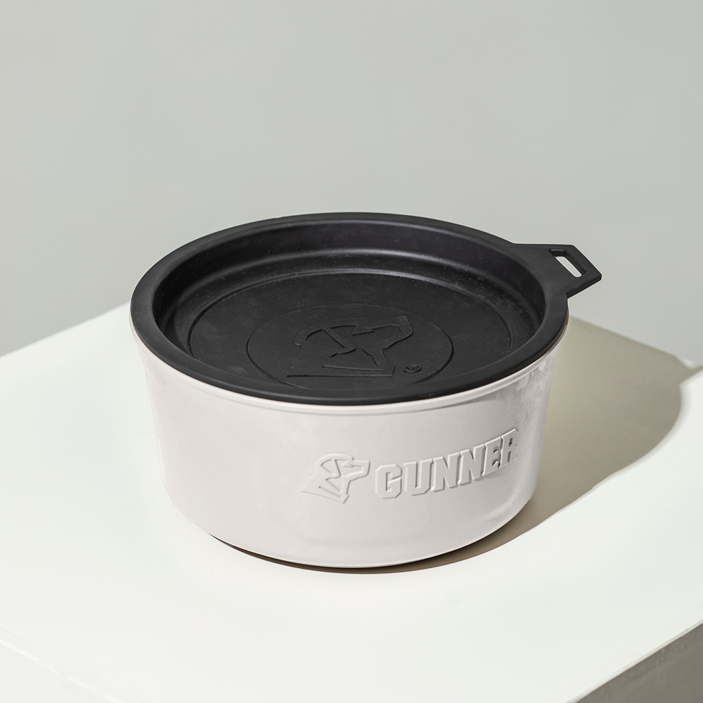 The GUNNER DOG BOWL - GUNNER YARD by GUNNER is a round, light gray dog bowl with a spill-proof lid and black top, featuring the embossed word GUNNER and logo on its side. It is displayed on a white surface.