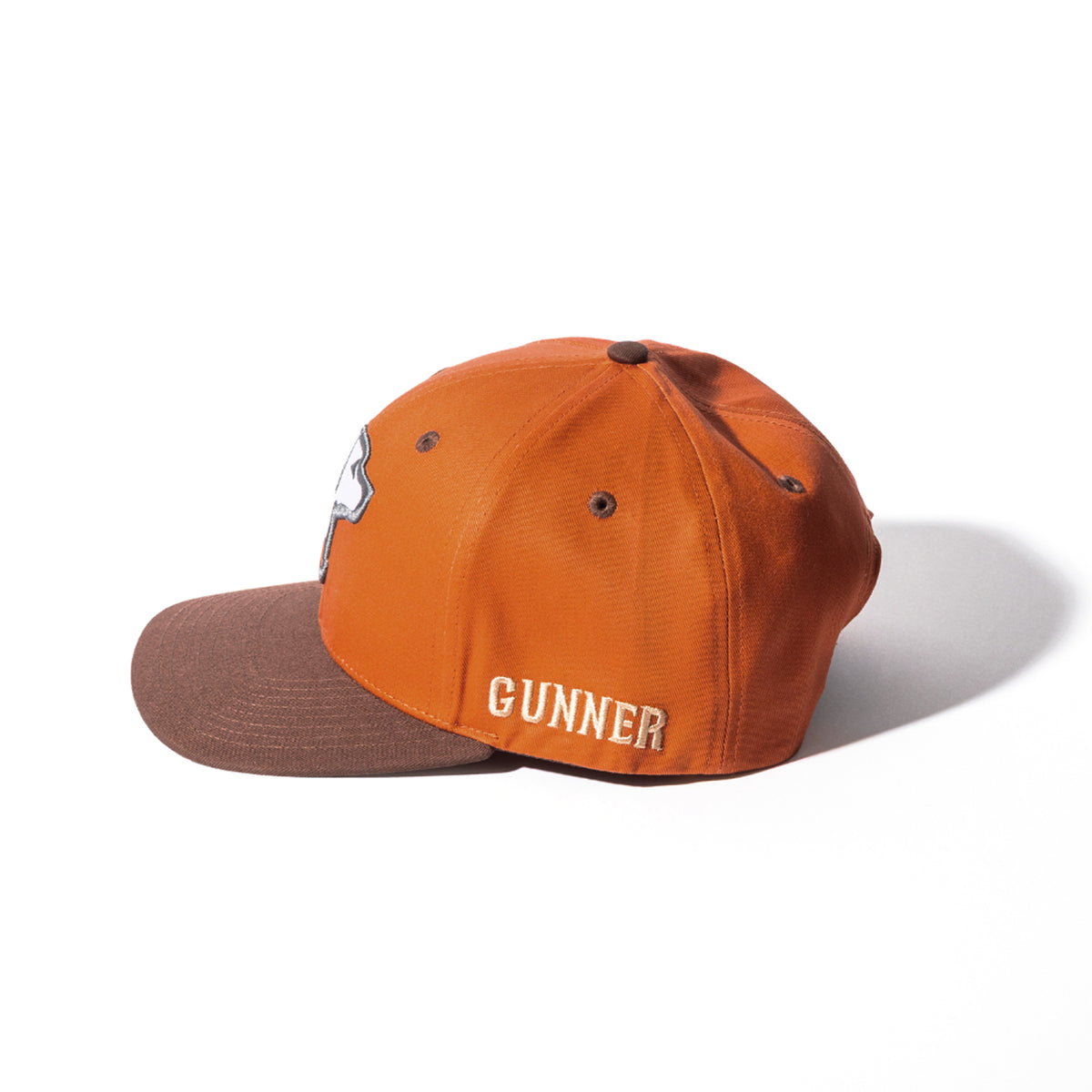 An orange HUNT SOLIDS Snapback by GUNNER features a brown brim and GUNNER embroidered in white and yellow on the side. The GUNNER cap is shown on a white background.