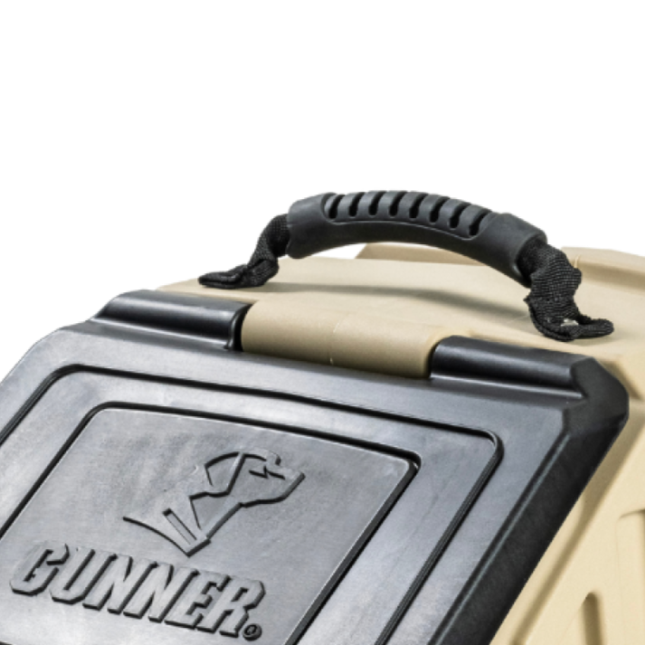 Close-up of a tan and black pet carrier with a sturdy, textured Food Crate Handle by GUNNER on top. The door features the GUNNER dog outline logo. The background is plain white.