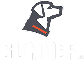 Stylized illustration of a hunting dogs head in profile, facing right, wearing an orange collar. The word GUNNER is written in bold white letters below the image, evoking the spirit of a reliable kennel companion.
