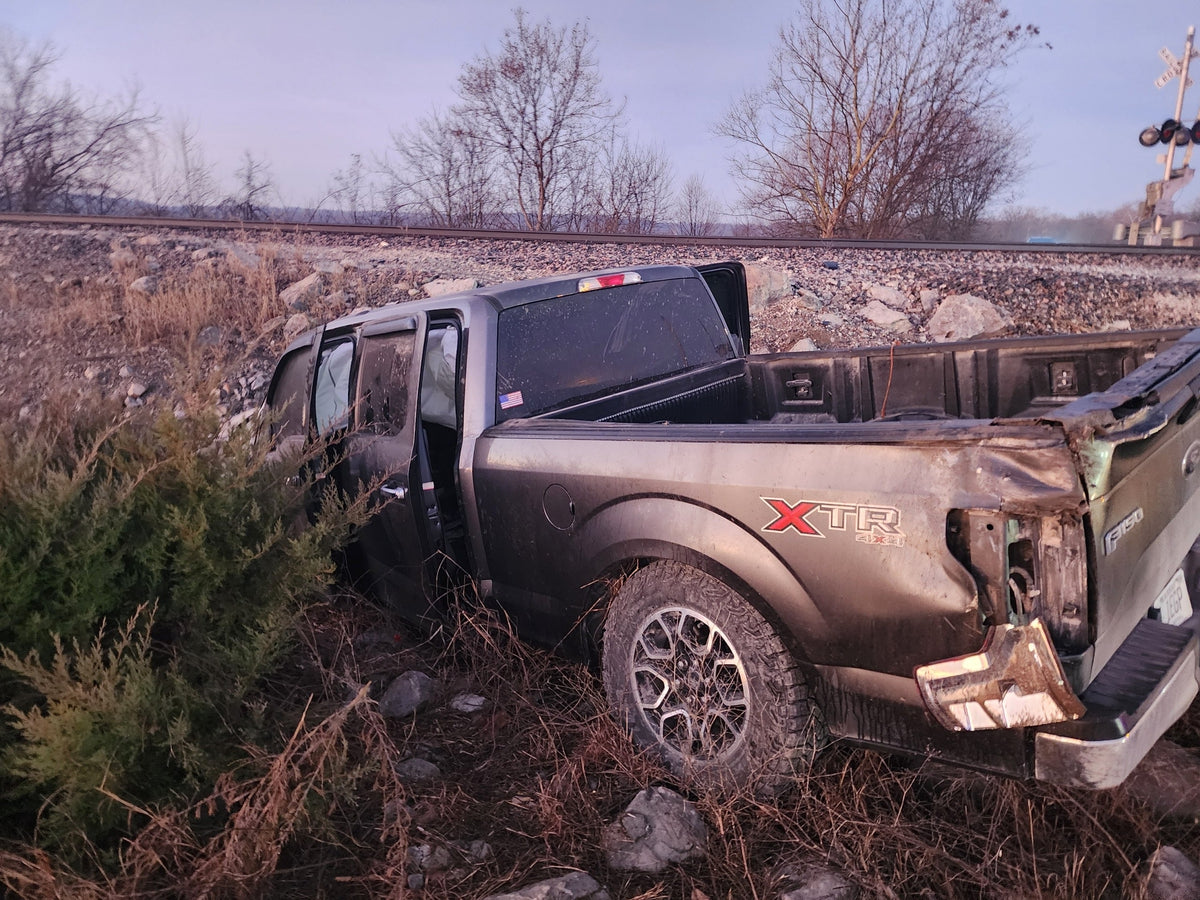 Gray Ford F-150 in a ditch on the side of a road after a wreck