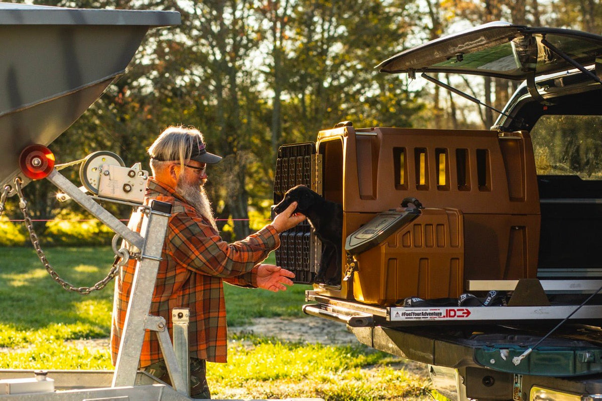 Jeff Coats pets a Black Labrador Retriever who is standing in the back on a G1™ Kennel in Susquehanna brown in the back of a pickup truck.