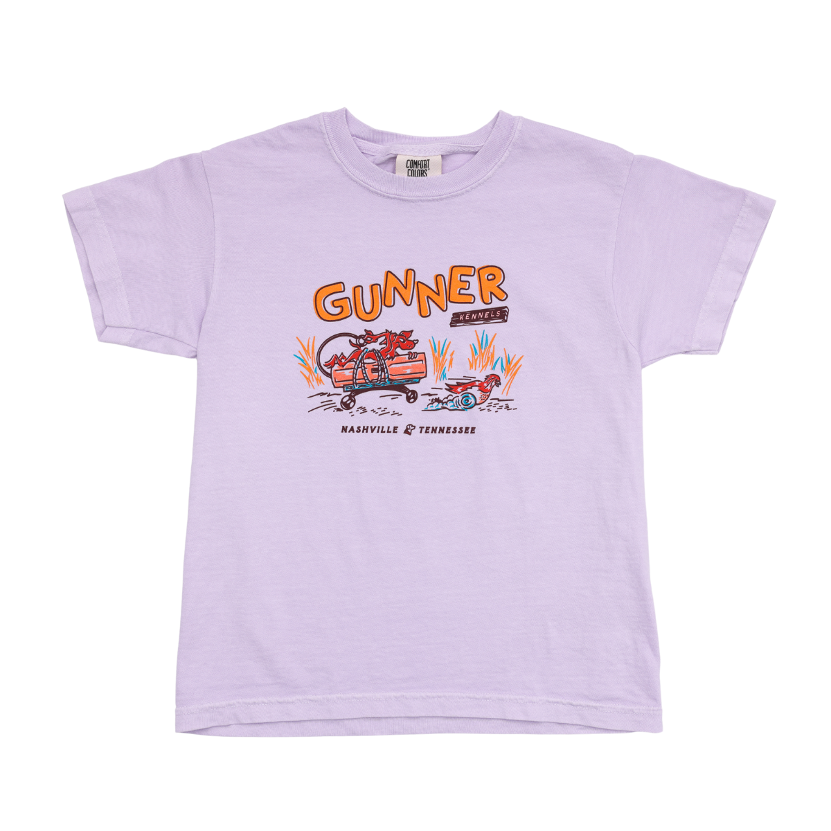The BUMPER DYNAMITE TEE (Kids) by GUNNER features a light purple design with an illustrated red dinosaur driving a red car, bold orange GUNNER text, and NASHVILLE TENNESSEE printed below—great for young fans.