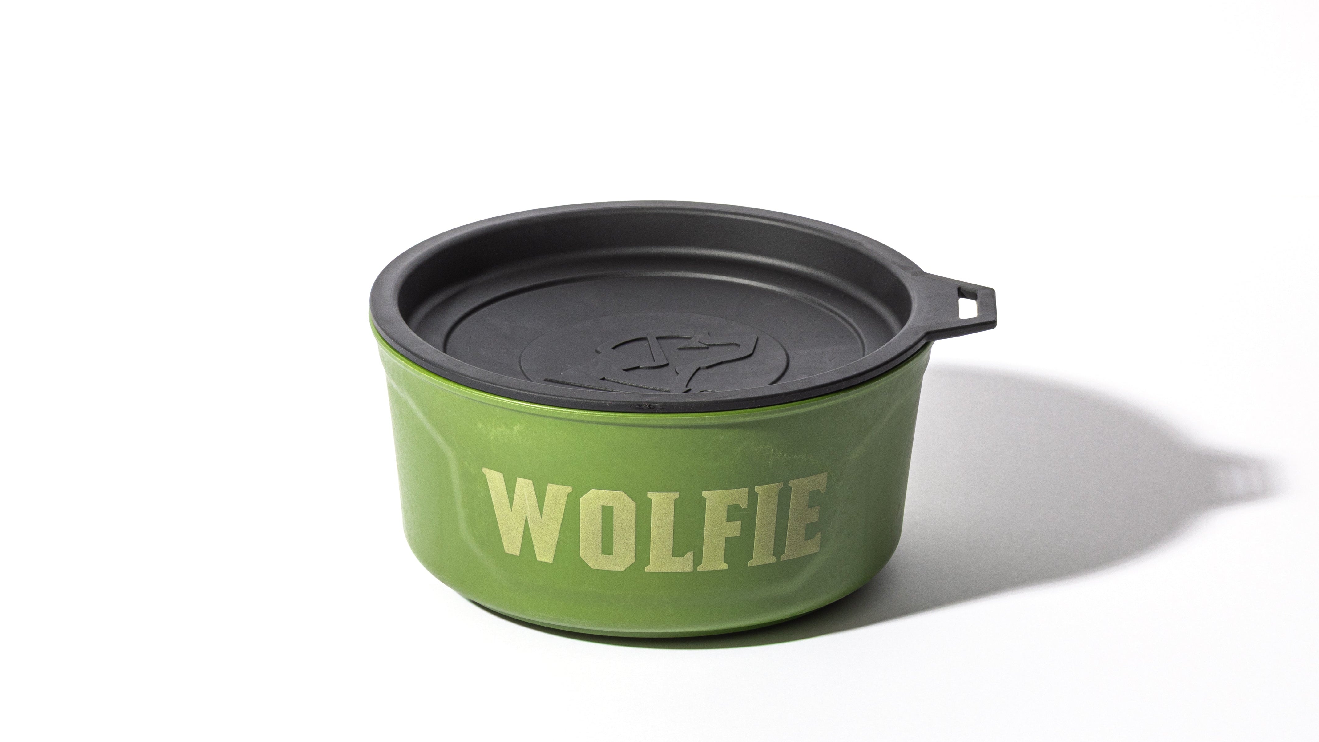 A green container with a black lid and small handle, featuring the word WOLFIE in bold white letters on the side, perfect for storing outdoor gear or supplies for your working dog, set against a white background.