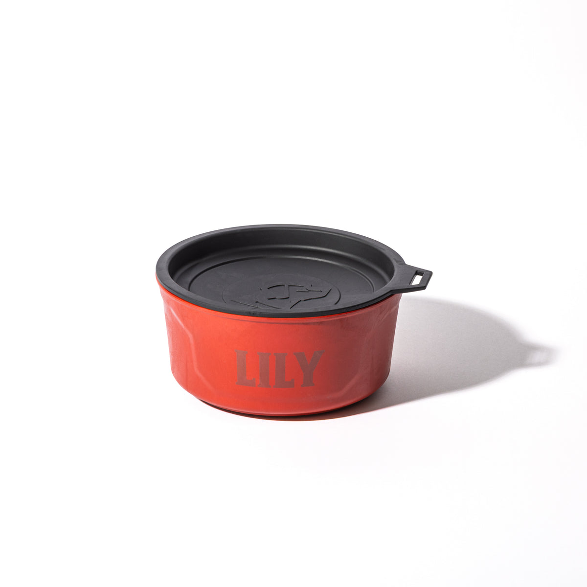 The GUNNER DOG BOWL - Red by GUNNER, a round travel bowl with a black lid and LILY printed on the side, sits on a white background. Ideal for dogs on the go, its part of the Color Fetch 2025 collection.