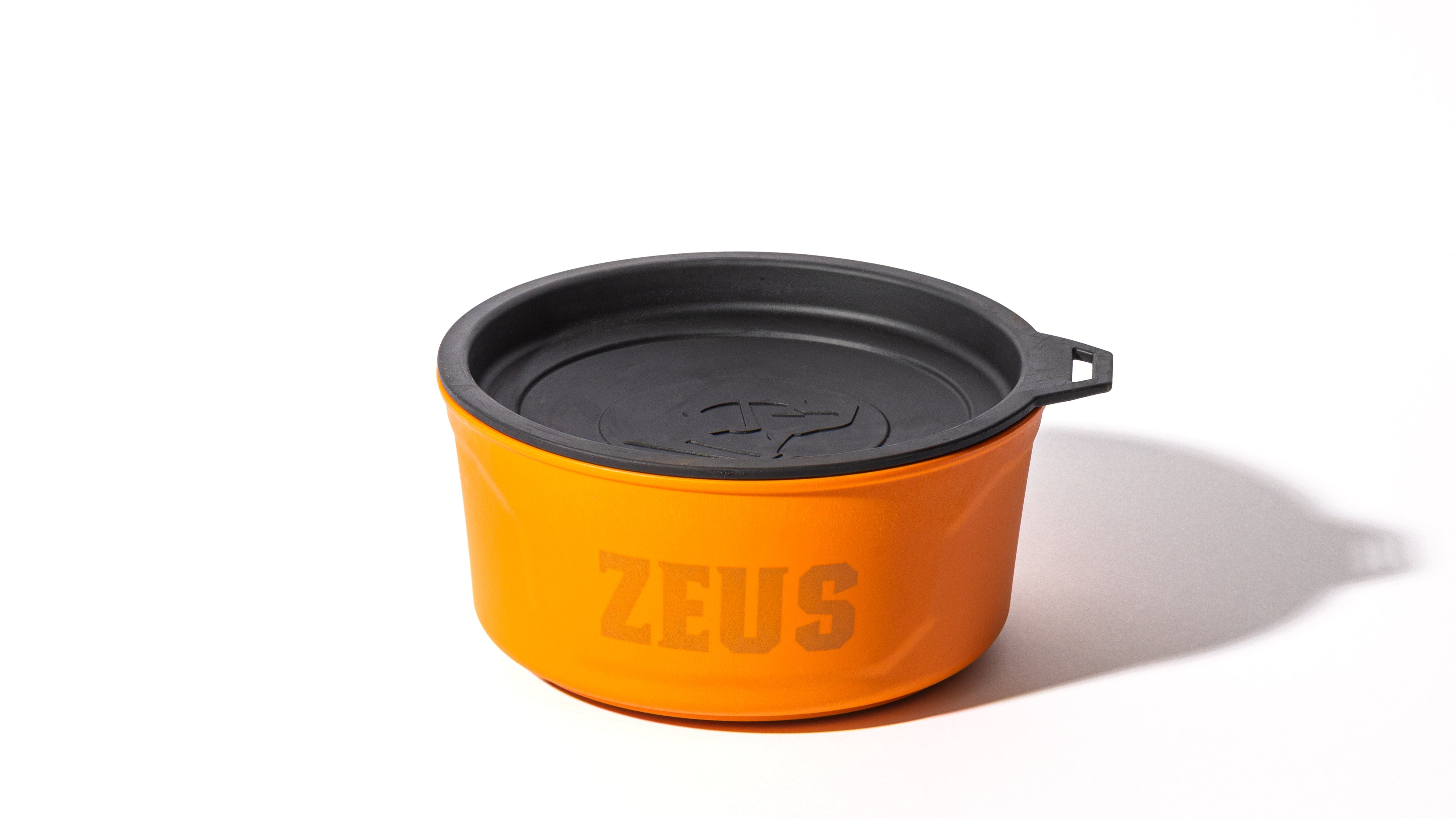 An orange container with a black lid and a handle on the side, featuring the word ZEUS printed in large letters on the front—perfect for storing your outdoor gear or dog kennel essentials. The container casts a shadow on a white background.