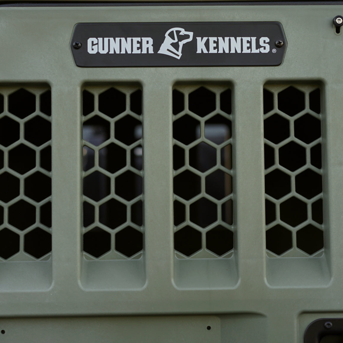 Close-up of the GUNNER G1™ KENNEL DOOR GREEN, featuring a hexagonal mesh design and a black and white Gunner logo plaque with a stylized dog head above the vents.