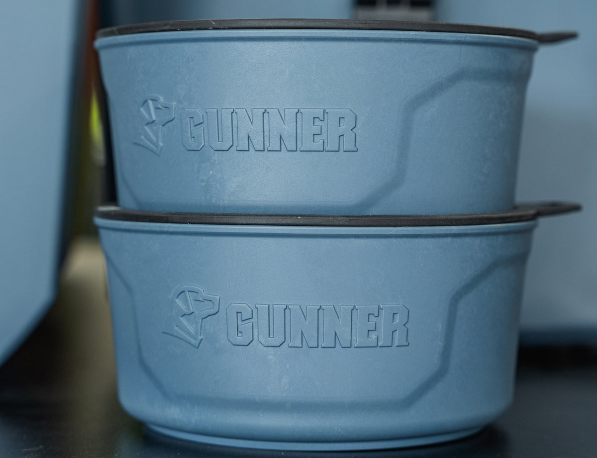 The GUNNER DOG BOWL - Ducks Unlimited Blue by GUNNER features two stacked blue bowls with GUNNER embossed on the side—ideal for any Ducks Unlimited or waterfowl habitat supporter’s dog.