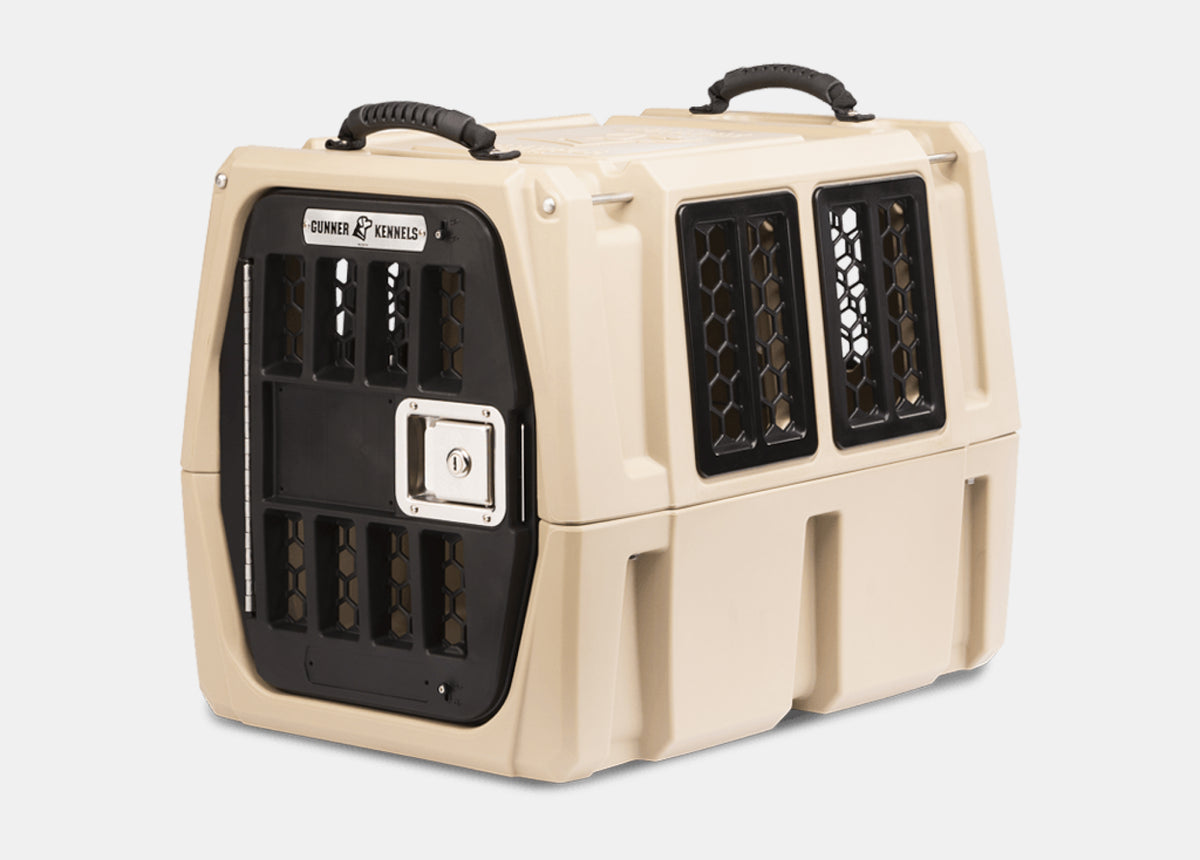 A beige and black hard-sided dog crate with a secure metal door, air vents on the sides, and a handle on top for easy carrying—perfect as reliable outdoor gear or a comfortable kennel for your pet.