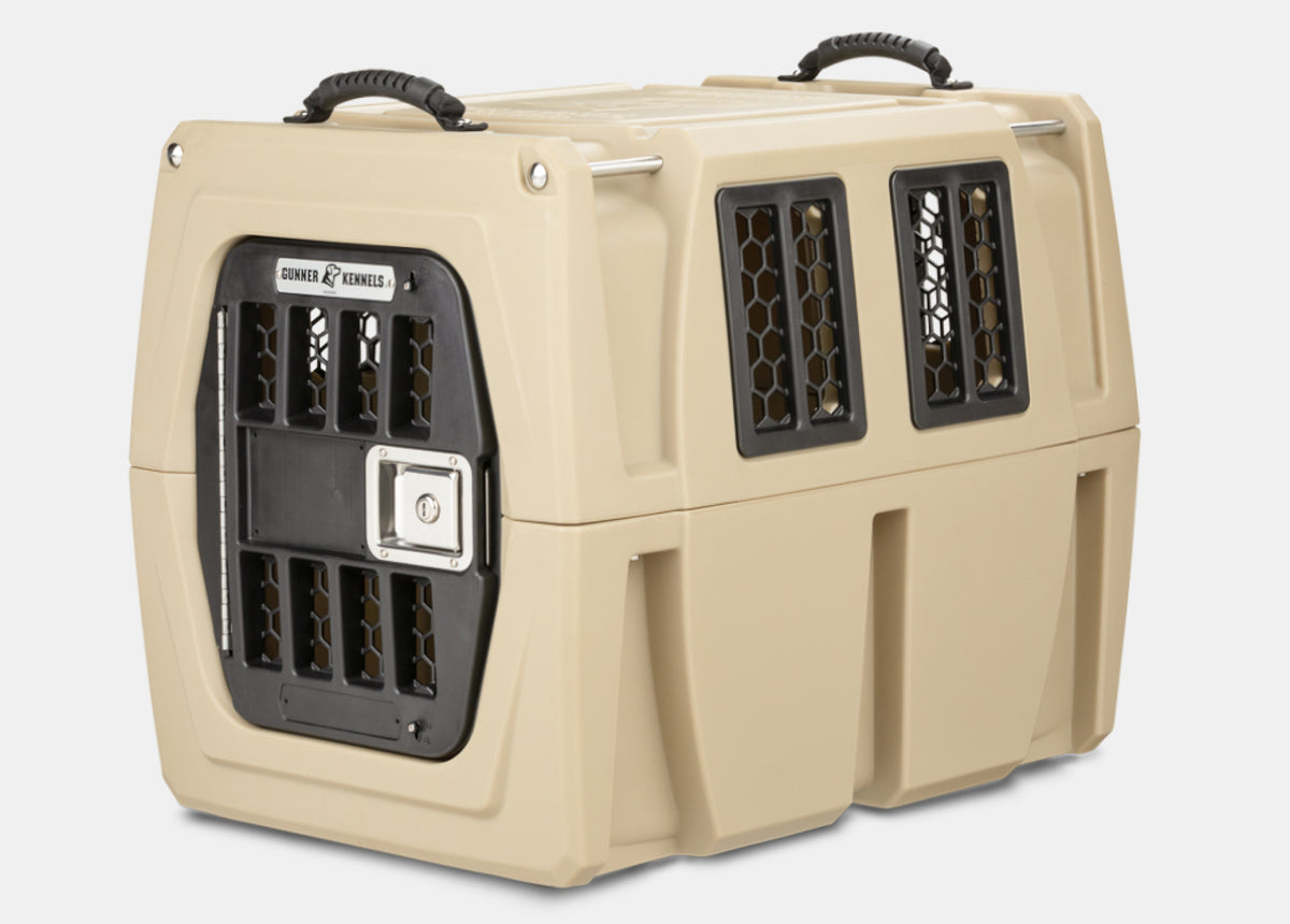 A sturdy, beige plastic pet kennel with black ventilation windows and a secure, metal door, designed for safely transporting animals. Ideal for outdoor gear or traveling with your hunting dog, it features handles on top for easy carrying.