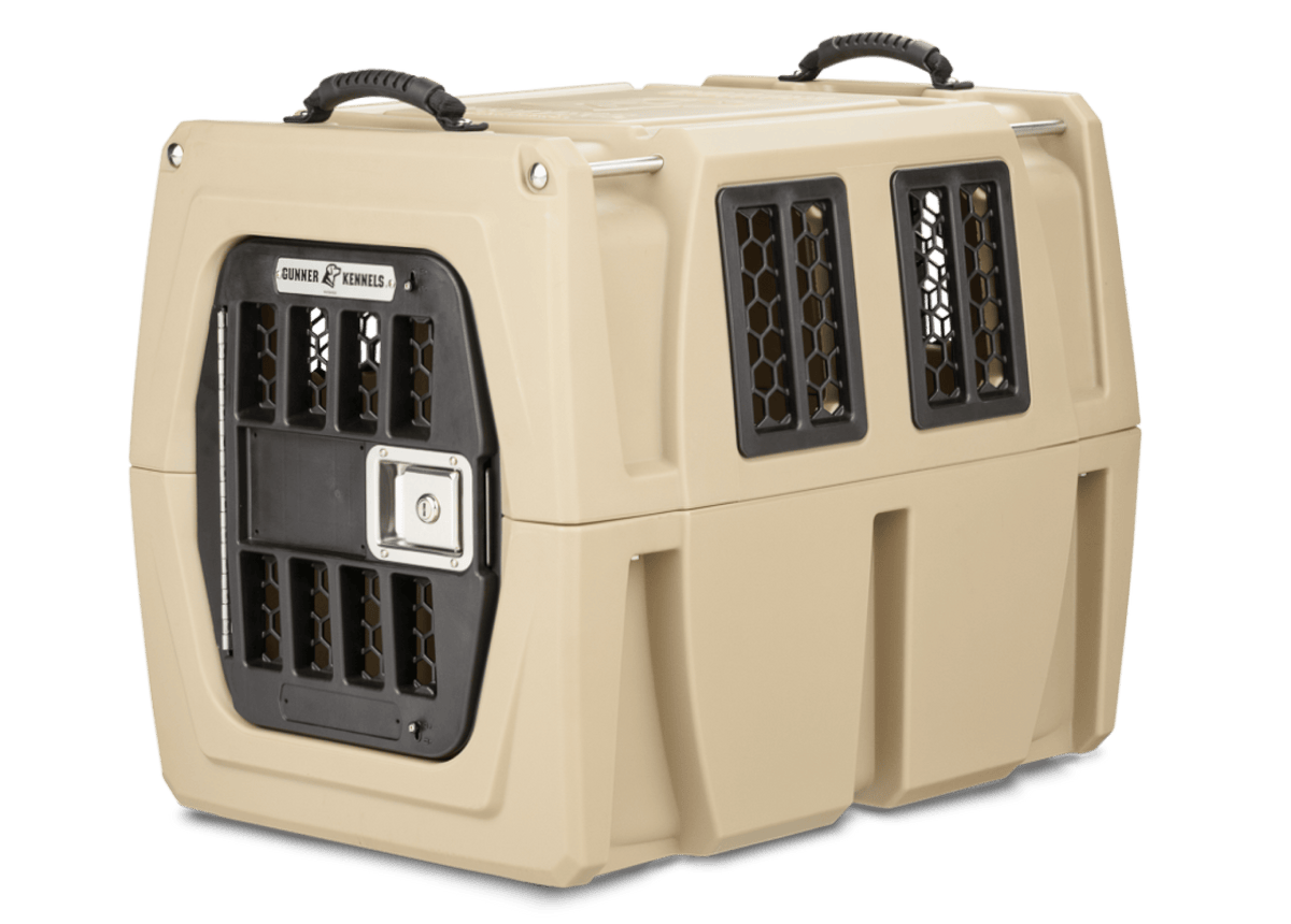 The GUNNER G1™ Kennel is a tan, hard-sided pet crate with black ventilation grilles, a secure metal door, and two top carrying handles. Its double-walled design offers outstanding shock protection for safe pet transport.