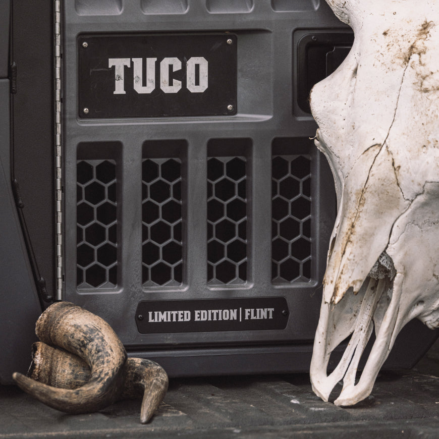 A metal case labeled TUCO and Limited Edition | Flint stands beside a large animal skull and a curled horn on a dark surface, evoking the spirit of classic outdoor gear prized by every seasoned hunter or loyal hunting dog.