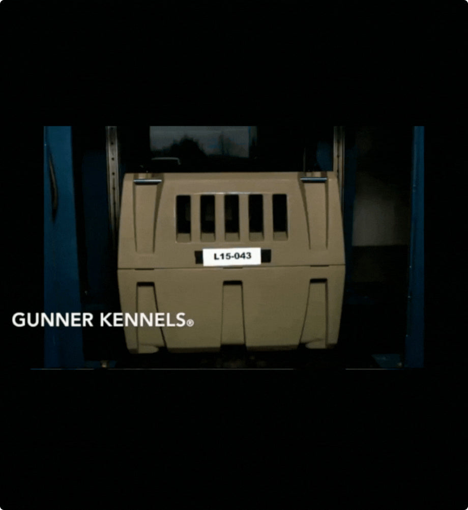 A tan Gunner Kennels dog crate for hunting dogs, labeled L15-043, is positioned inside a blue testing apparatus, with GUNNER KENNELS® displayed on the left side of the image.