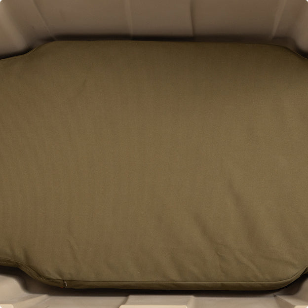 A close-up of an olive-green cushion inside a light beige plastic dog crate. The cushion is rectangular with rounded edges and fits snugly within the crate, providing comfort for a hardworking hunting dog or working dog.