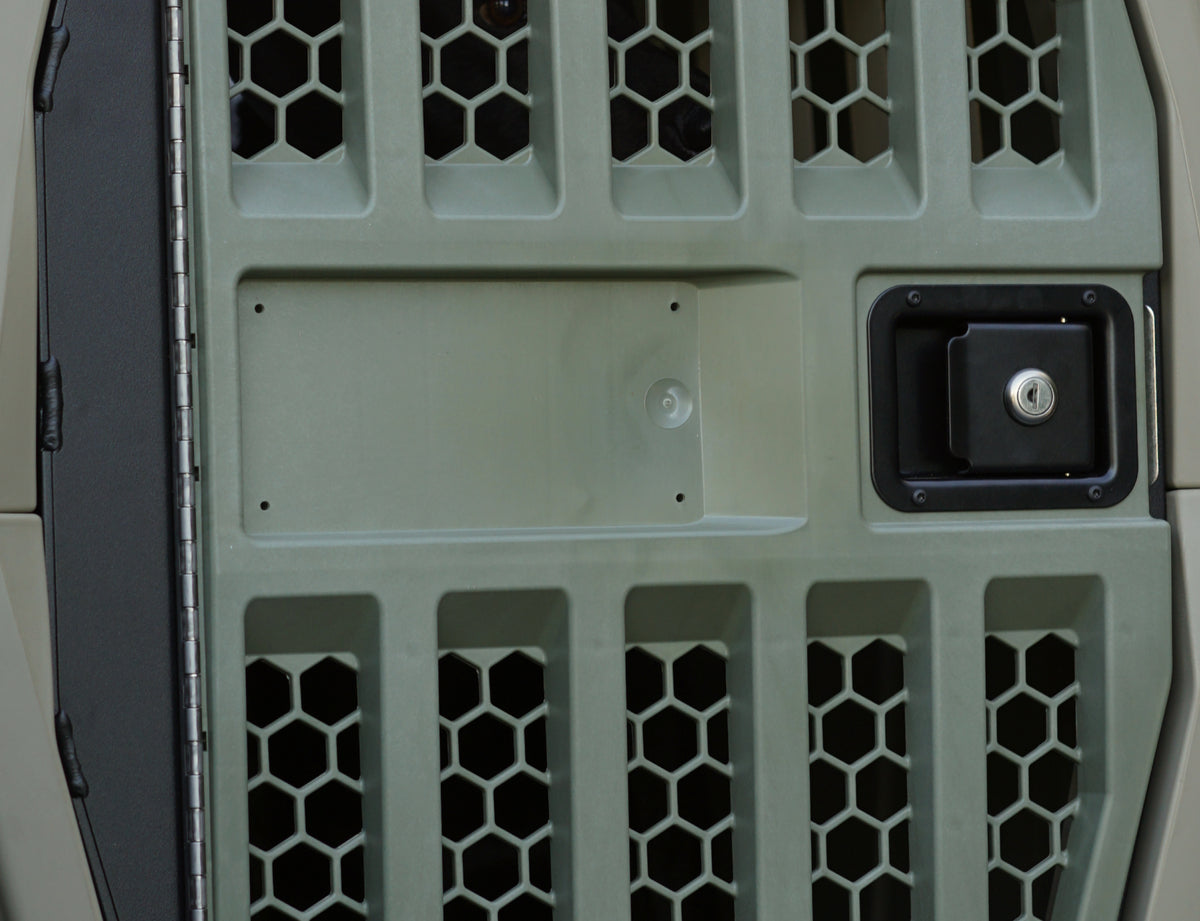 Close-up of the GUNNER G1™ KENNEL DOOR GREEN, featuring hexagonal vent grid, recessed rectangular panel, and square black handle with keyhole on a matte olive-green finish.