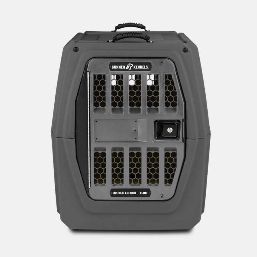 A sturdy gray dog crate with a secure metal door, ventilation holes, and a handle on top—perfect for transporting your loyal working dog. The label reads Gunner Kennels Limited Edition Flint.