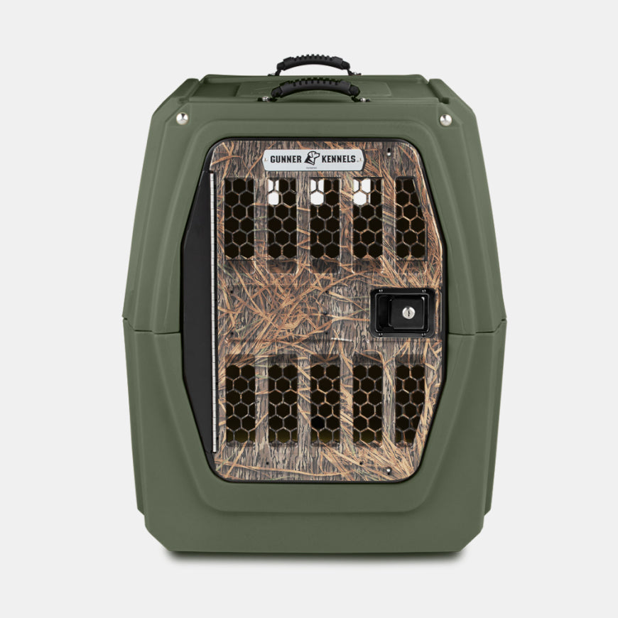 Green hard-sided dog crate with a front door featuring hexagonal ventilation holes and a camouflage pattern, labeled Gunner Kennels. Perfect for outdoor gear enthusiasts, shown against a plain white background.
