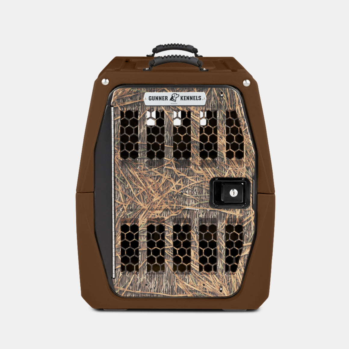 The G1™ KENNEL - SUSQUEHANNA/MOSSY OAK SHADOW GRASS by GUNNER features a brown body, a front door with Mossy Oak Shadow Grass camo, ventilation holes, and Gunner branding—ideal for duck hunters—shown on a plain white background.