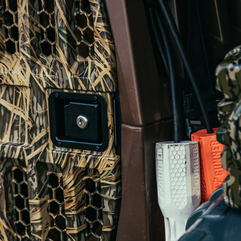 Close-up of the GUNNER G1™ KENNEL in SUSQUEHANNA/MOSSY OAK SHADOW GRASS, featuring a black lock and thick, color-coded cables—perfect for duck and goose hunters seeking secure transport.
