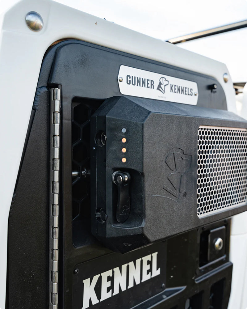 Close-up of a black and white dog crate door featuring a latch with indicator lights, metal mesh vent, and a “GUNNER KENNELS” logo plate above the word “KENNEL”—ideal outdoor gear for any hunting dog.