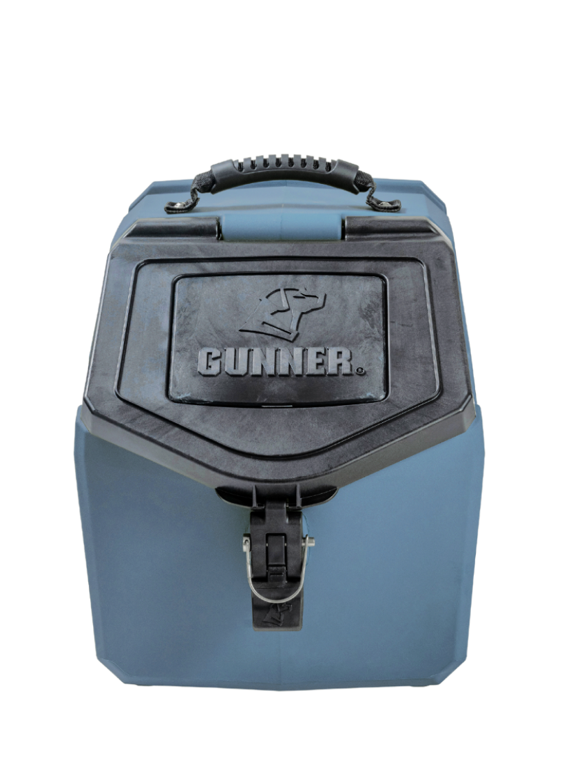 A blue and black hard-sided dog kennel with a top handle and latch, featuring the brand name GUNNER and a dog silhouette on the front panel. The container is photographed against a plain white background.