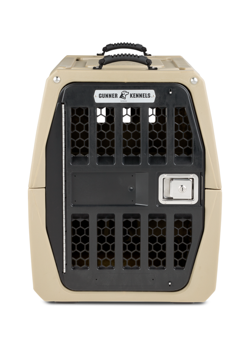 A tan and black hard-sided dog crate with a metal door, black ventilation holes, a silver latch, and a handle on top. The label above the door reads Gunner Kennels—perfect for safely transporting your hunting dog.