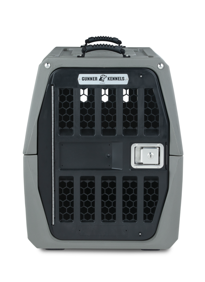 A sturdy, gray plastic dog crate with a black metal front door, honeycomb ventilation panels, a handle on top, and a label that reads Gunner Kennels—ideal outdoor gear for every adventure with your hunting dog.