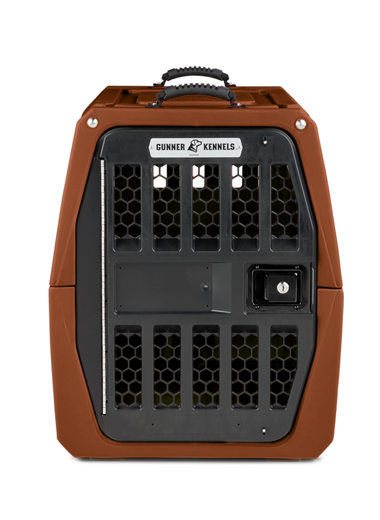 A sturdy, brown hard-shell kennel with a black metal door and hexagonal ventilation holes, labeled Gunner Kennels at the top, designed for working dogs and shown against a plain white background.