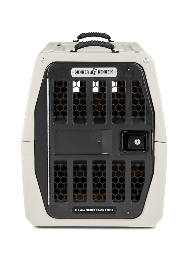 A sturdy, light gray dog crate with a black metal door and honeycomb ventilation holes, ideal for outdoor gear. Features a top handle and is labeled “Gunner Kennels” and “Flyway Series | Saskatoon” on the front.