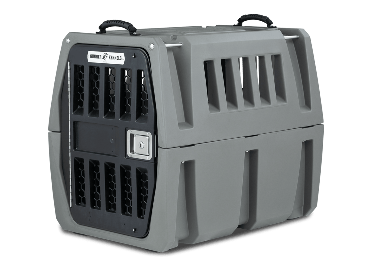 The GUNNER G1™ Kennel is a sturdy gray double-walled crate with black vents, a secure metal door, side vents, and two top handles—engineered by GUNNER YARD for maximum shock protection and safe pet transport.