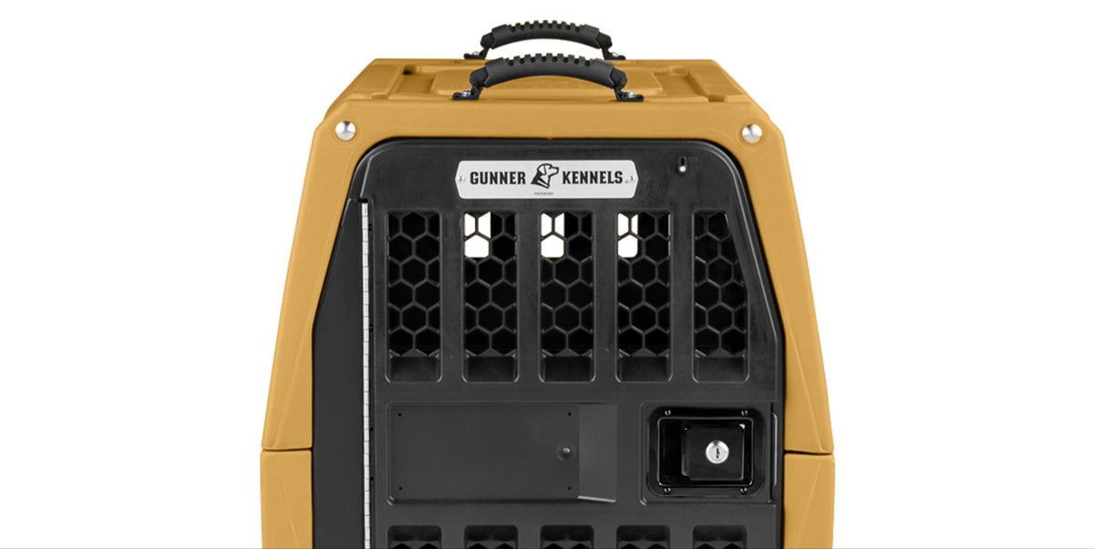 A heavy-duty tan and black dog crate with a honeycomb-patterned metal door, a sturdy handle on top, and a label that reads Gunner Kennels—perfect outdoor gear for your working dog or hunting dog.