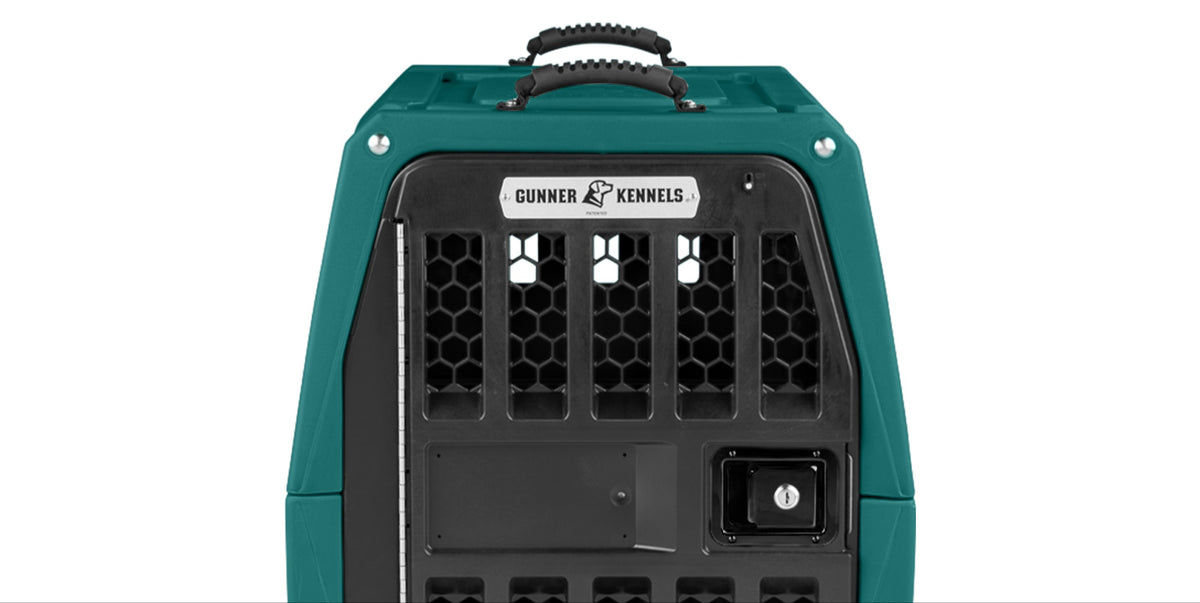 A teal-colored kennel travel crate with a black, vented metal door, carrying handle on top, and a Gunner Kennels label above the door—ideal for transporting your working dog—shown against a white background.