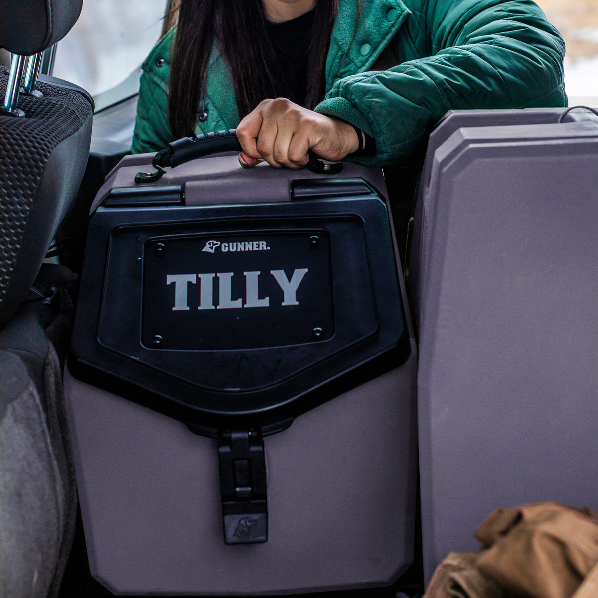 At dusk, someone in a green jacket loads a GUNNER FOOD CRATE - DUSK into the backseat, possibly after an outing with their companion.