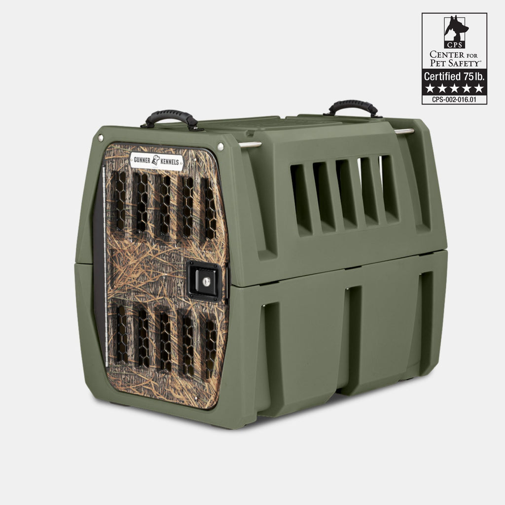 The GUNNER G1™ KENNEL in Gunner Green/Mossy Oak Shadow Grass has a tough, double-walled build, camo front door, ventilation slats, black handles, and is CPS-certified for dogs up to 75 lbs—one of the safest crates available.