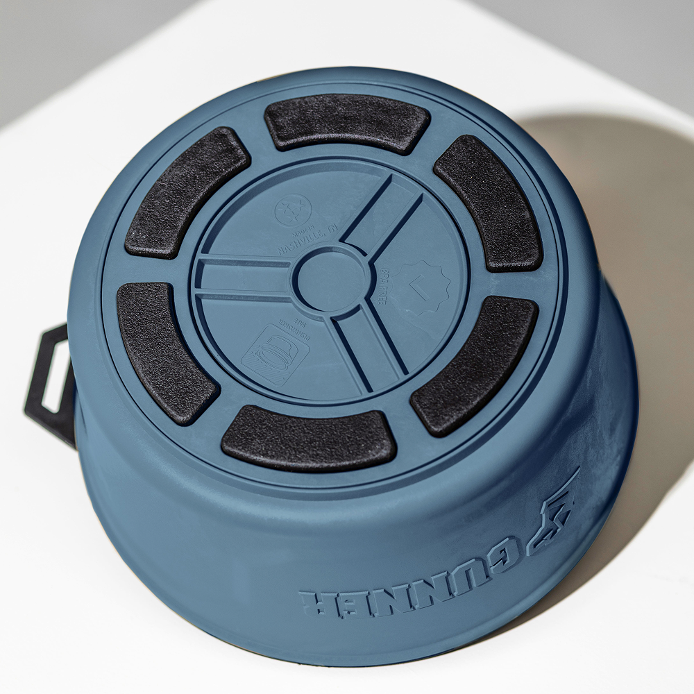 A Ducks Unlimited Blue GUNNER dog bowl by GUNNER is pictured upside down, featuring circular black rubber grips on the base and embossed center symbols.