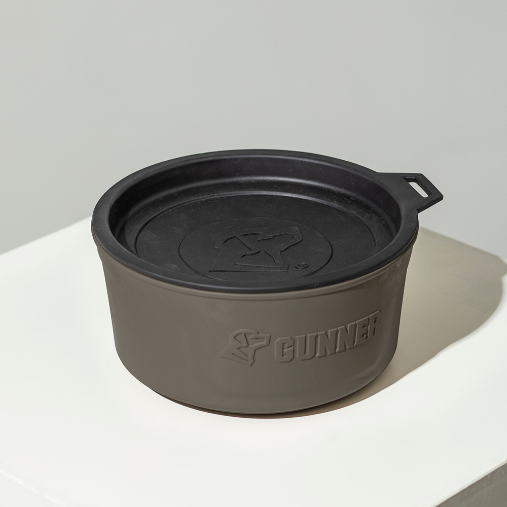 The GUNNER DOG BOWL - GUNMETAL, a round matte gray portable bowl with a black lid and embossed GUNNER logo, is displayed on a white surface against a neutral background.