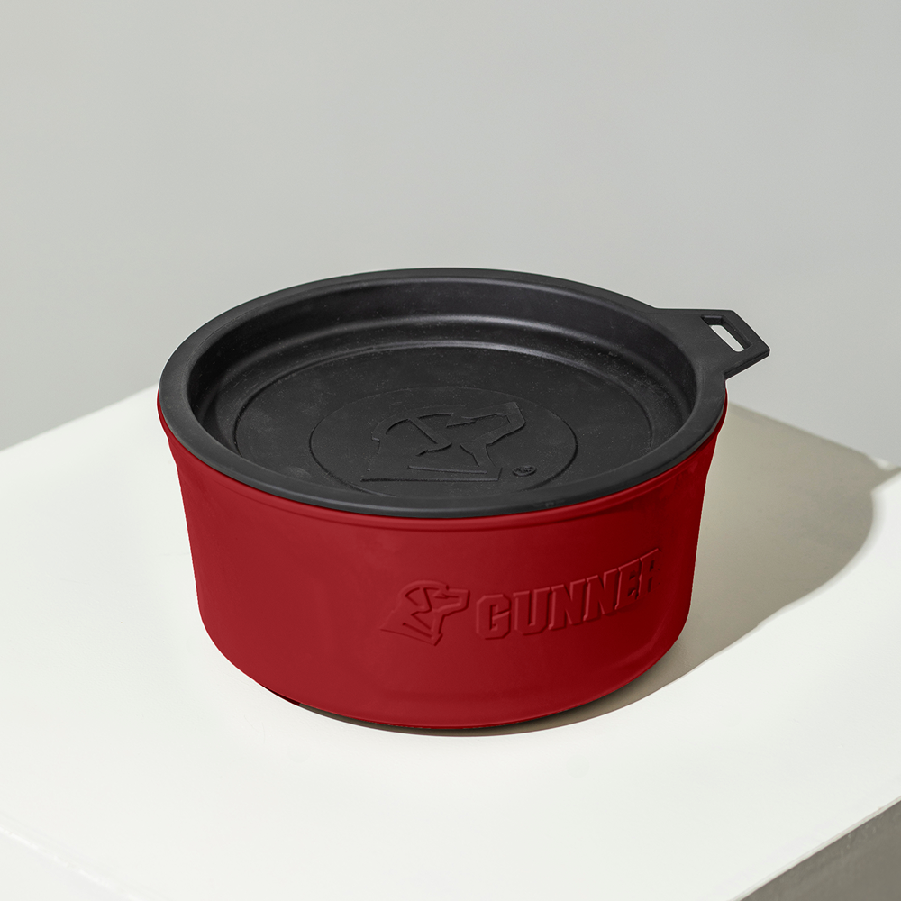 A GUNNER DOG BOWL - Red, a round travel bowl with lid and embossed GUNNER logo, sits on a white surface against a light gray background—a stylish choice from the Color Fetch 2025 collection.