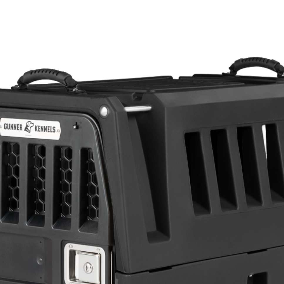 A close-up of a GUNNER KENNEL HANDLES - BLACK accessory attached to a G1 Kennel dog crate, highlighting its sturdy rubber handle, ventilation slats, secure latch, and durable construction against a plain background.
