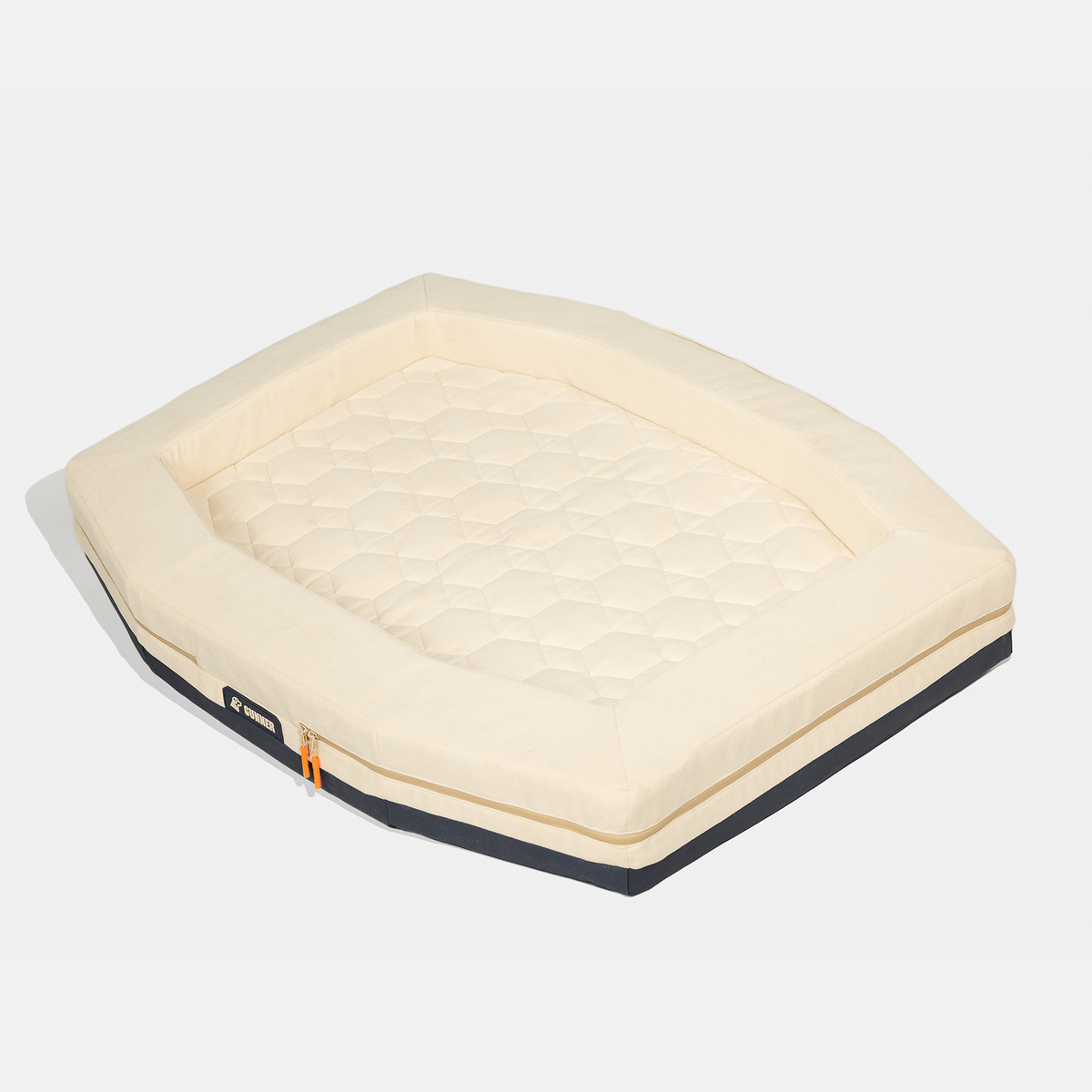 The GUNNER HOMESTEAD DOG BED Oak is a rectangular, cream-colored pet bed with cushioned sides, a quilted base, black bottom edge, and a small orange zipper pull. Durable and easy to clean, it’s perfect for daily use.