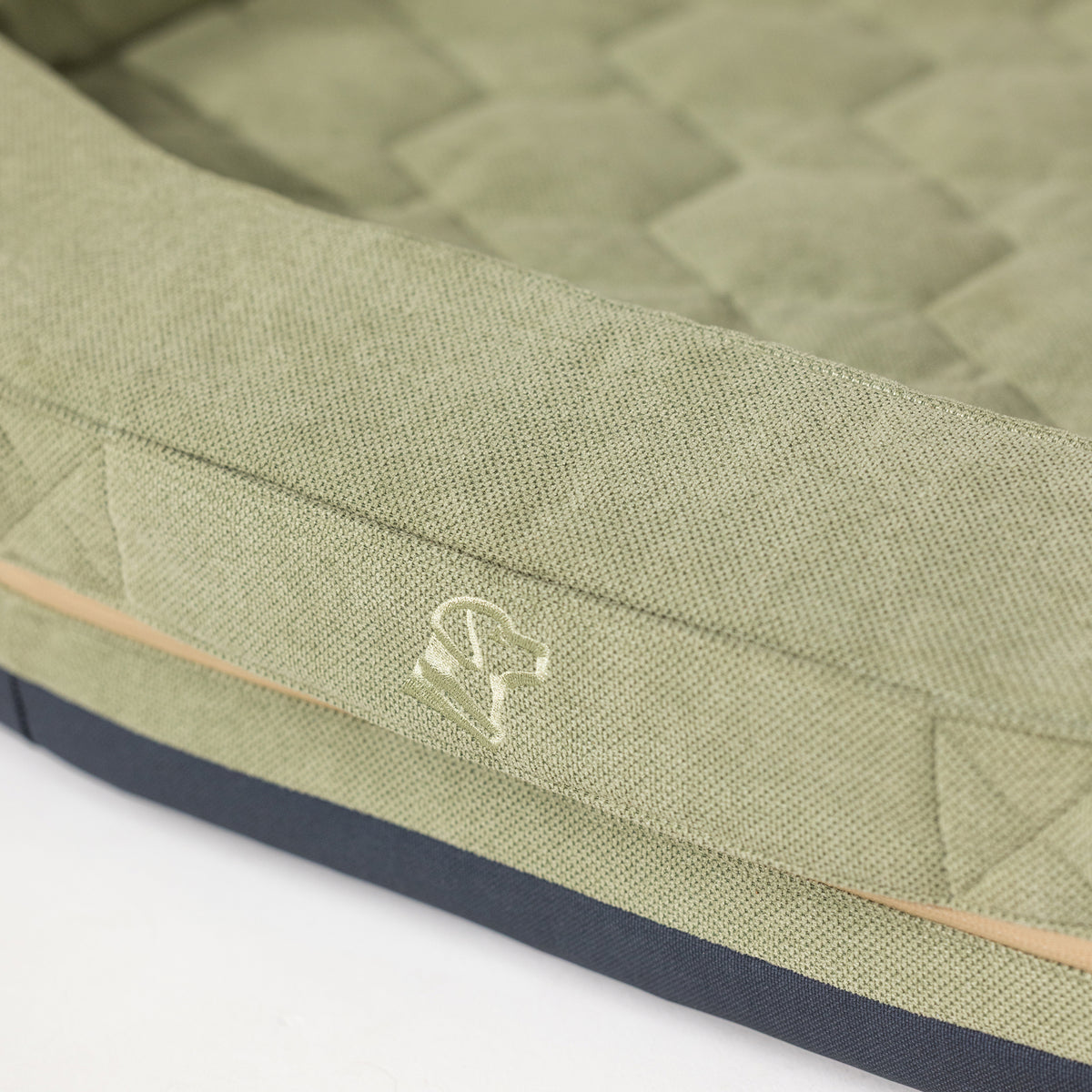 The GUNNER HOMESTEAD DOG BED Treeline Green features a quilted green fabric with a stitched dog head outline, beige border, and dark blue base—creating a durable, easy-to-clean pet bed.