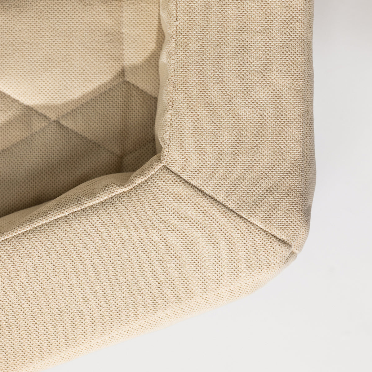 Close-up of the corner of the beige HOMESTEAD DOG BED Oak by GUNNER, highlighting its hexagonal, textured fabric, sturdy stitching, and soft upholstery. The durable material makes this dog bed long-lasting against a plain white background.