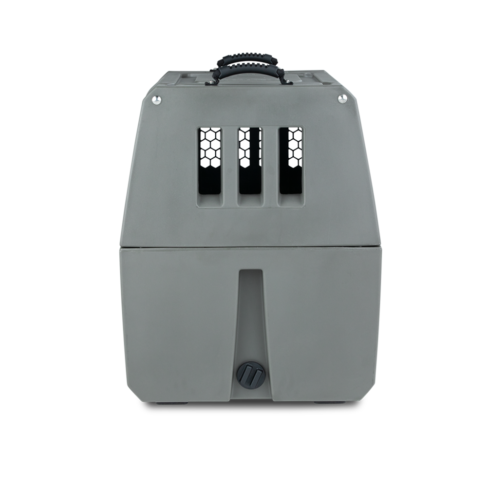 The GUNNER G1™ KENNEL - GUNMETAL is a gray plastic dog crate featuring a top handle, three vertical slits, front ventilation holes, and a black twist lock at the bottom for secure pet transport.