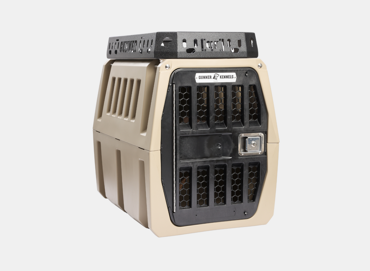 A tan and black hard-sided dog kennel with a secure metal door and ventilation holes, designed for safely transporting animals.