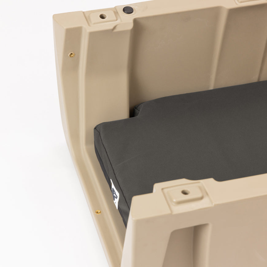 A close-up of a beige plastic dog crate with a black cushion inside, showing part of the cushion and the sturdy, thick sides of the container.