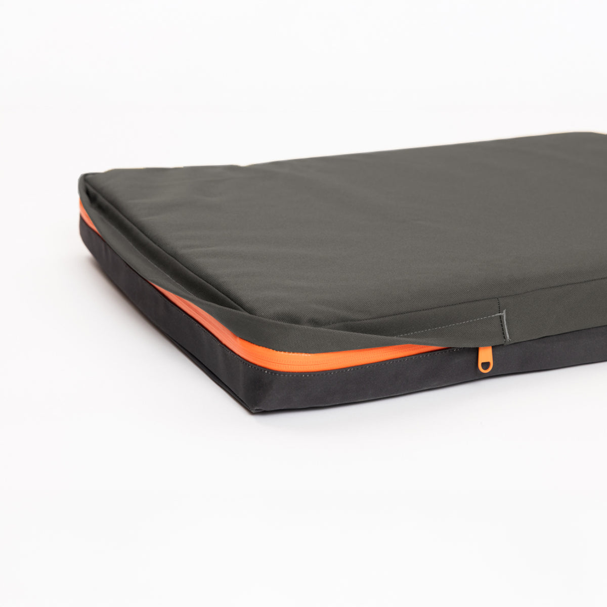 A black and dark gray rectangular laptop sleeve with an orange zipper, inspired by rugged outdoor gear, photographed on a white background.