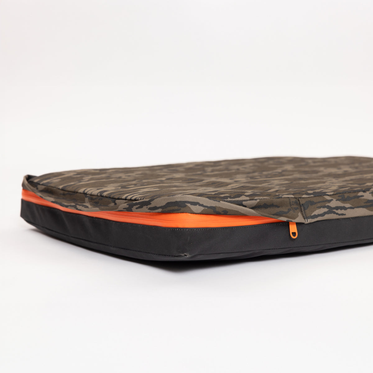 A flat camouflage-patterned laptop sleeve with an orange zipper lies on a white background, partially unzipped to reveal the interior—perfect for stowing your device alongside other outdoor gear, whether youre heading to the office or the hunting dog kennel.