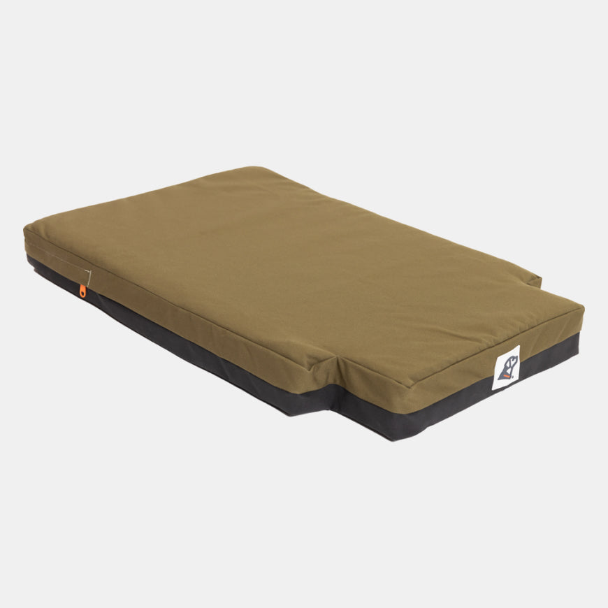 A rectangular, olive green pet bed with a black base and a small white logo patch on one corner, designed to fit perfectly inside a dog crate—ideal for providing comfort to your working or hunting dog, and displayed on a plain white background.