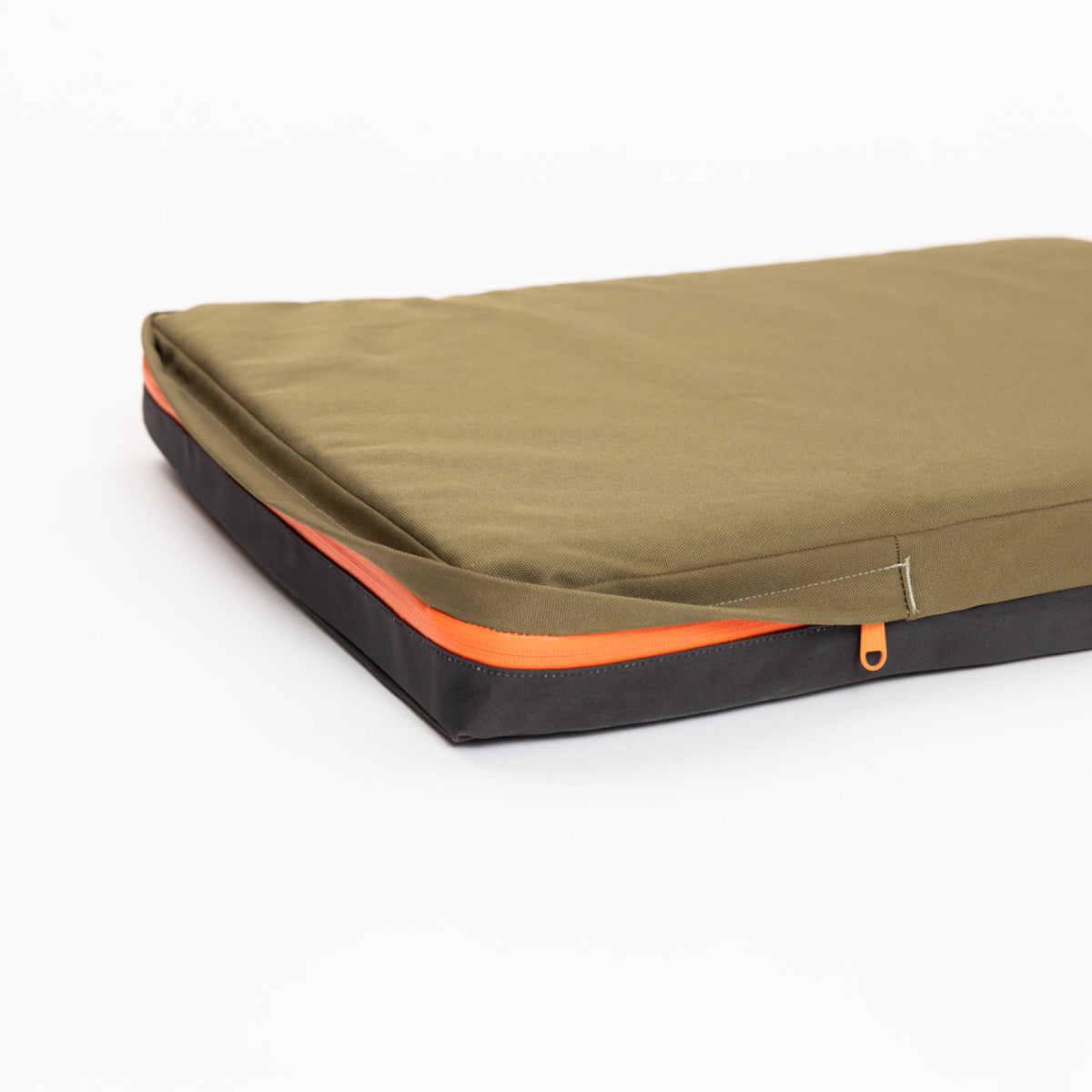 A slim, olive green and black laptop sleeve with an orange zipper, reminiscent of classic hunting dog gear, lying closed on a white surface.