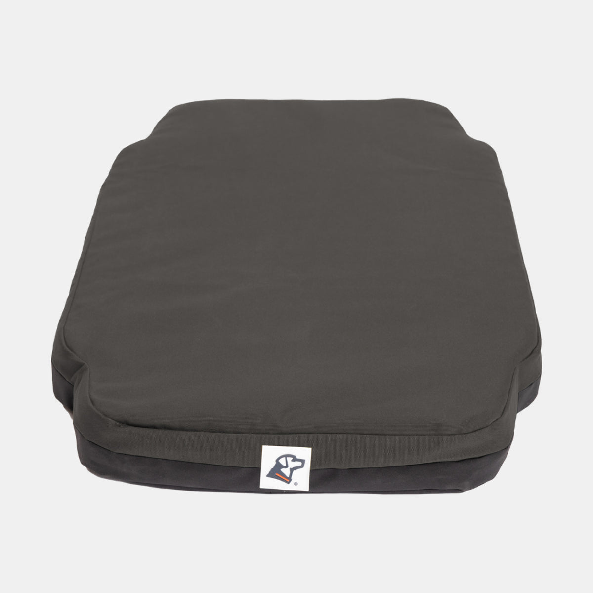 A rectangular, dark gray dog bed with slightly raised edges and a small tag featuring a dog logo at the front center—ideal for providing your working dog with comfort after a long day. The background is plain white.